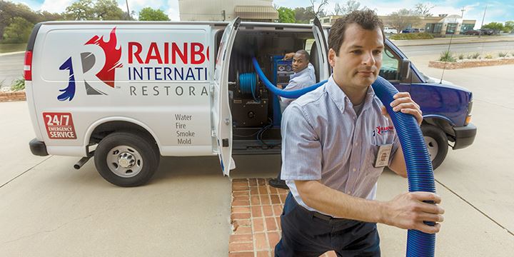 water damage restoration professionals from rainbow international restoration of buffalo carry a pump to a flooded home